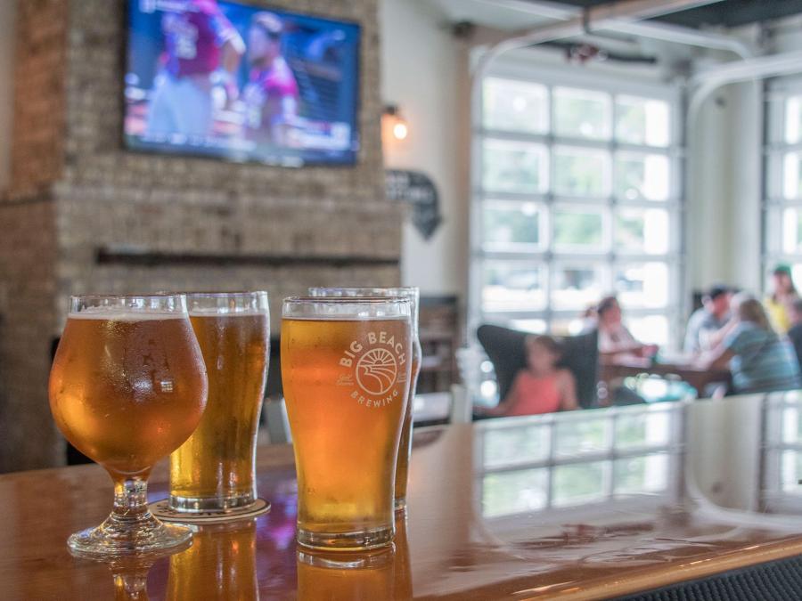 Draft beers on the bar with football playing on the TV at Big Beach Brewing in Gulf Shores