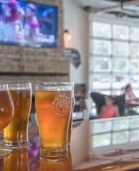 Draft beers on the bar with football playing on the TV at Big Beach Brewing in Gulf Shores