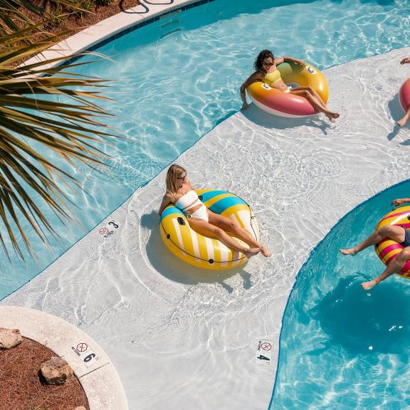 Friends floating in the lazy river at Beach Village Resort beach house community in Orange Beach