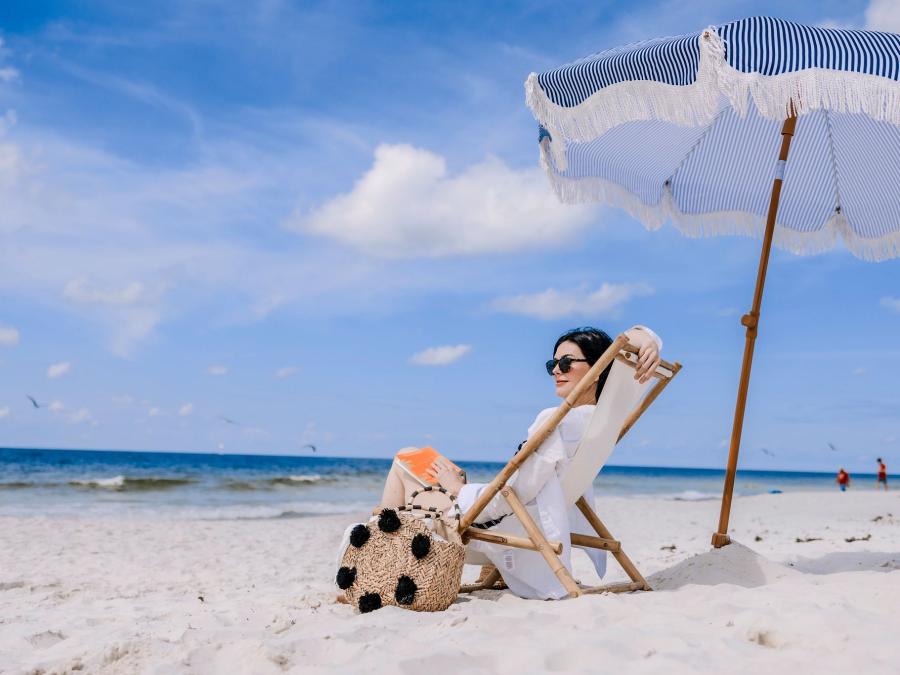 woman relaxing on the beach in a chair under an umbrella looking at the shore