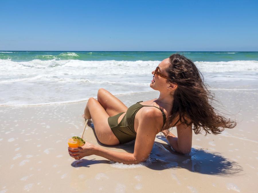 Woman laying in the sand with a cocktail on the beach in Gulf Shores