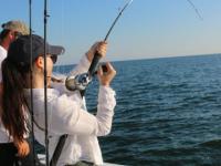 angler reeling in a fish during a deep-sea fishing charter trip in Orange Beach
